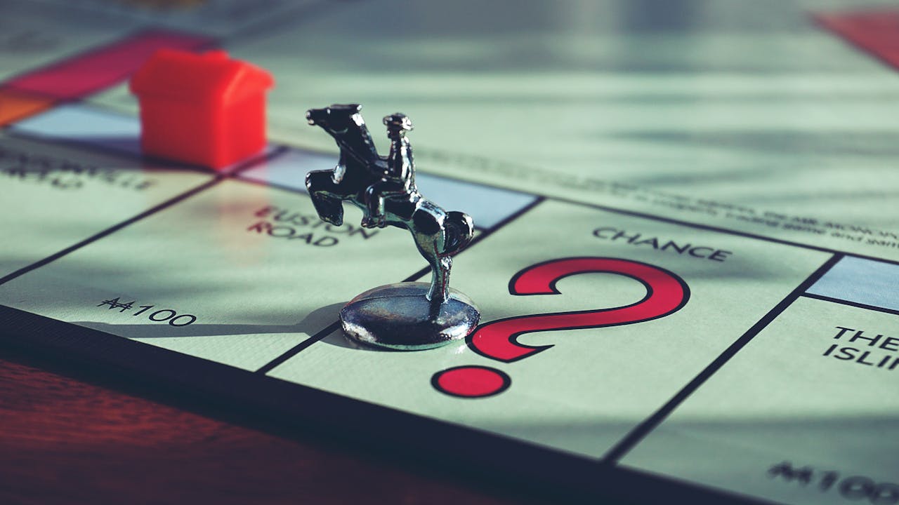 Close-up of a Monopoly board with a token and house, capturing classic board game elements.